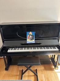 Svart akustiskt piano med pall bortskänkes.